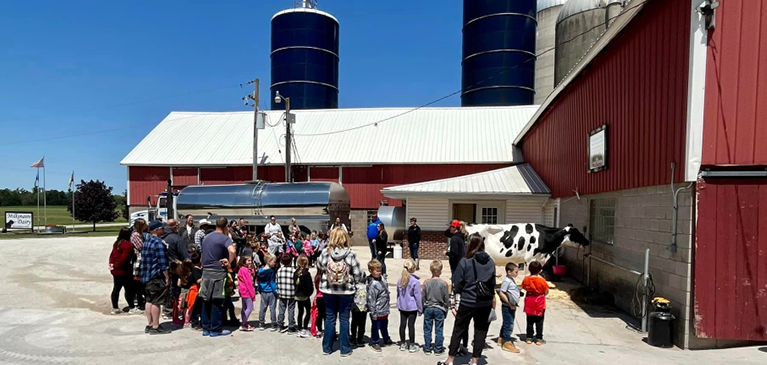 Kids standing in front of a dairy cow