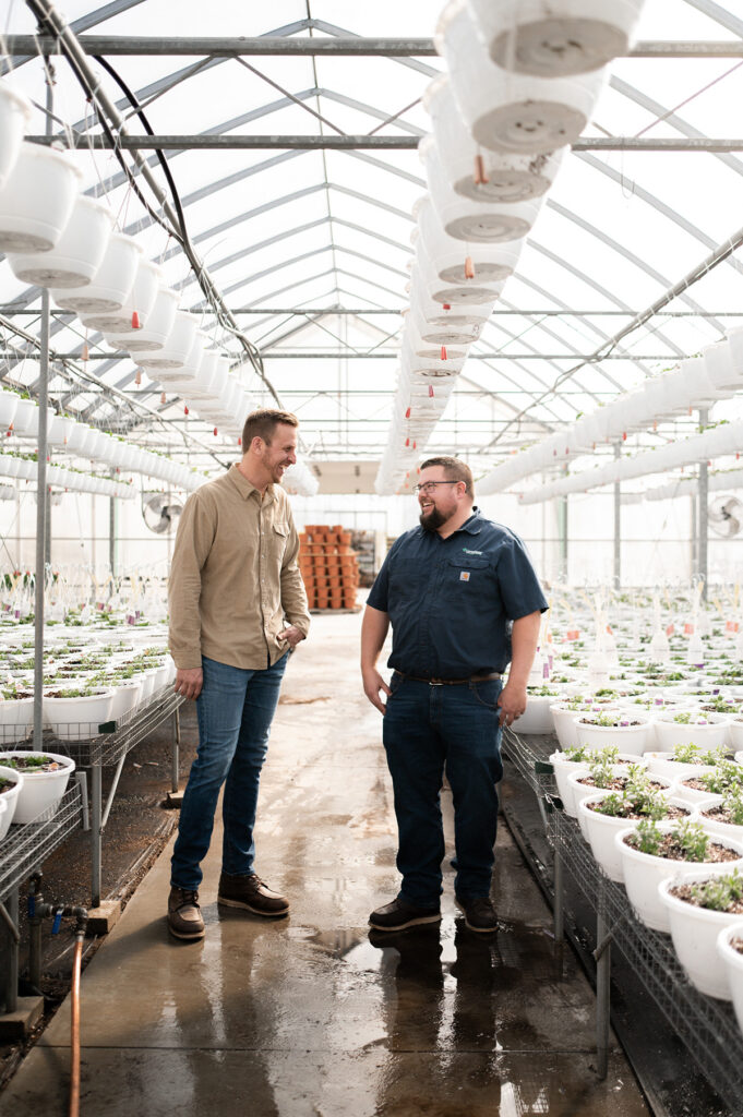 A GreenStone employee and member smiling and talking in a greenhouse