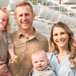 Young family of four stands in a greenhouse