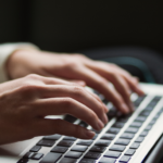 Person's hands typing on a laptop keyboard