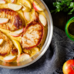 Apple cider braised pork shoulder in bowl with apples on the table