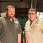Nick and Ken stand in front of asparagus in their packing facility