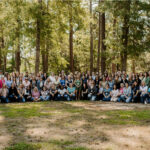 Large group of women posing for a photo in the woods
