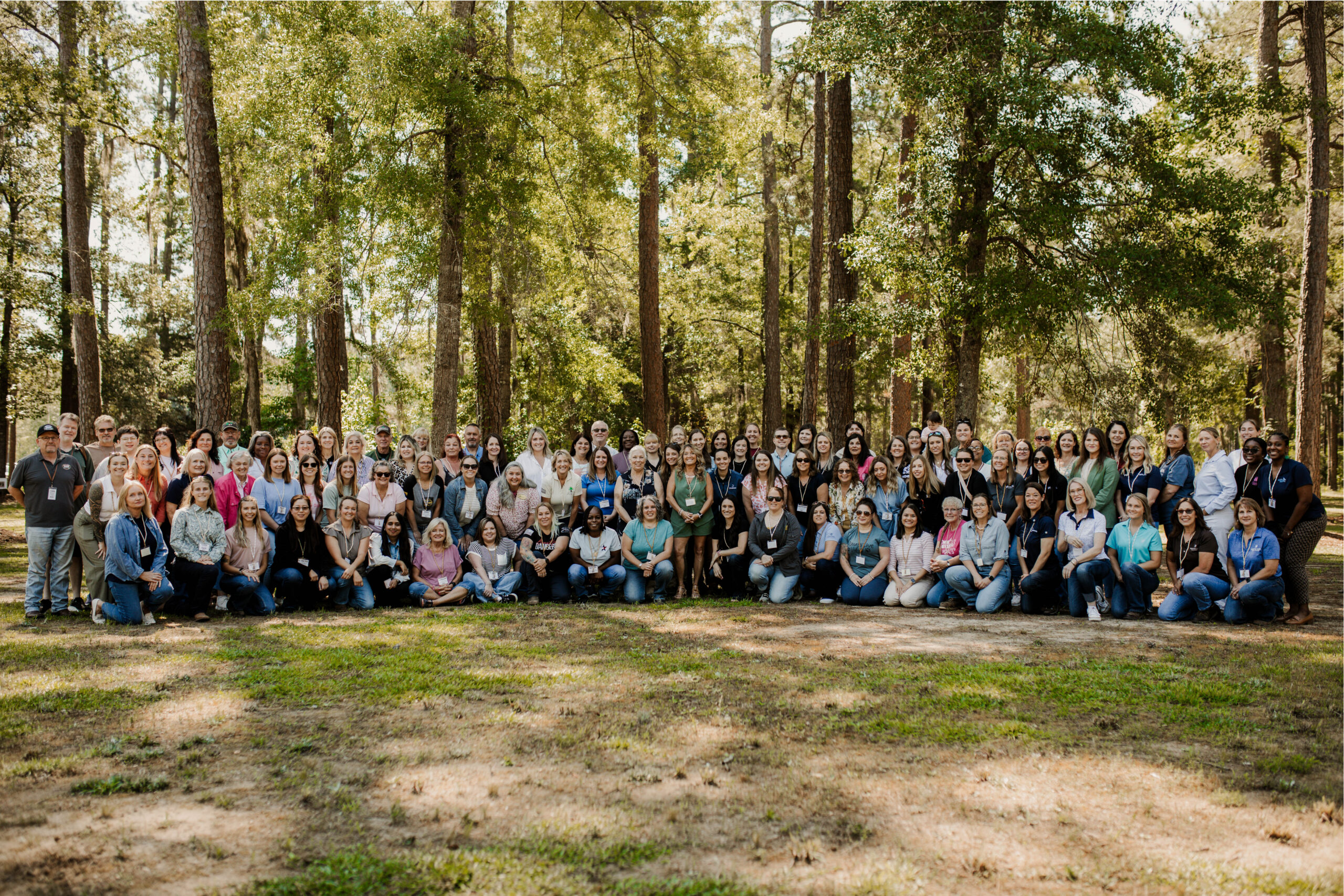 Large group of women posing for a photo in the woods
