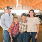 Family standing in a barn with dairy cows