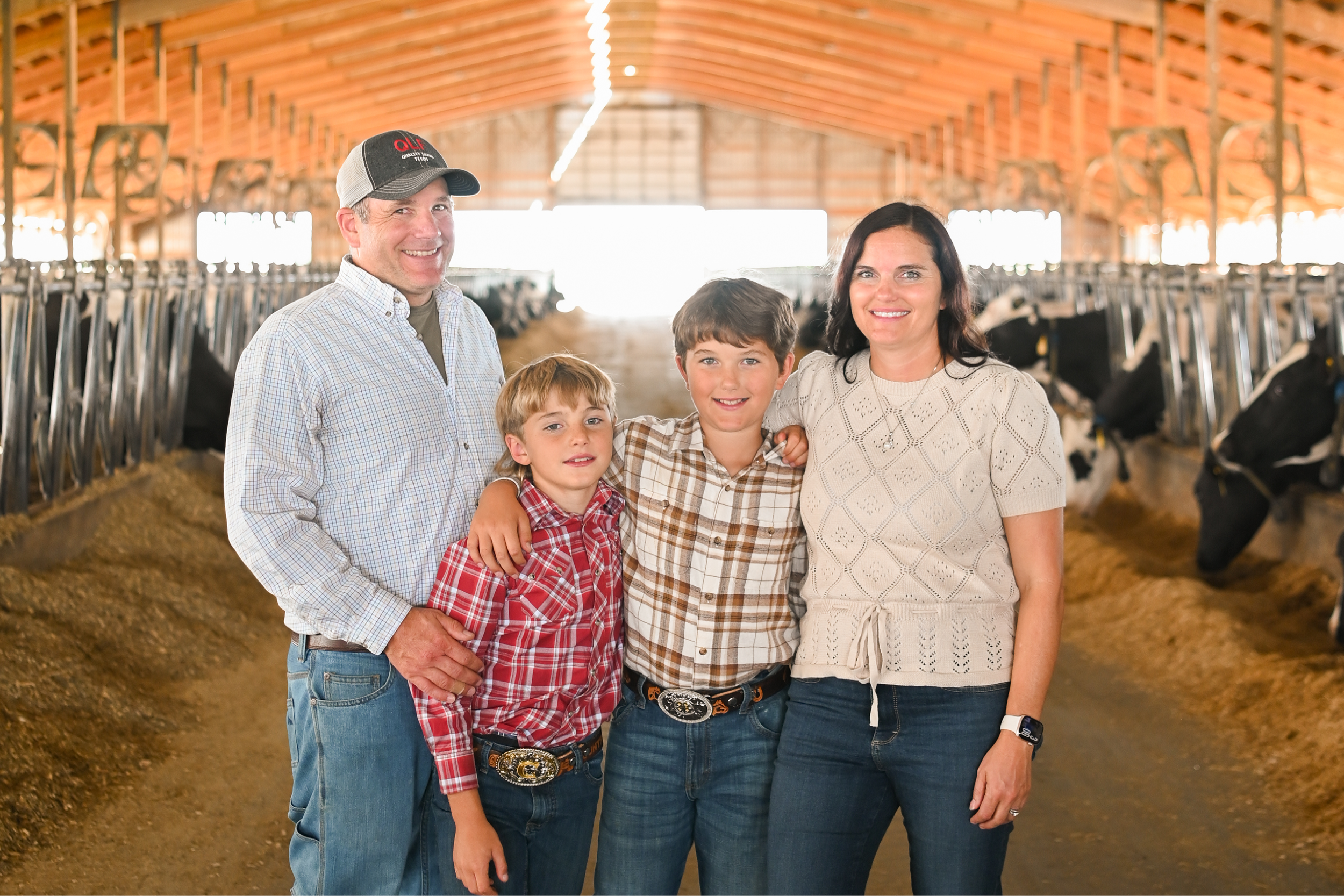 Family standing in a barn with dairy cows